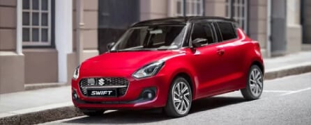 Carro Suzuki Swift híbrido de color rojo en una calle, como ejemplo de los vehículos usados que se pueden comprar en Colombia